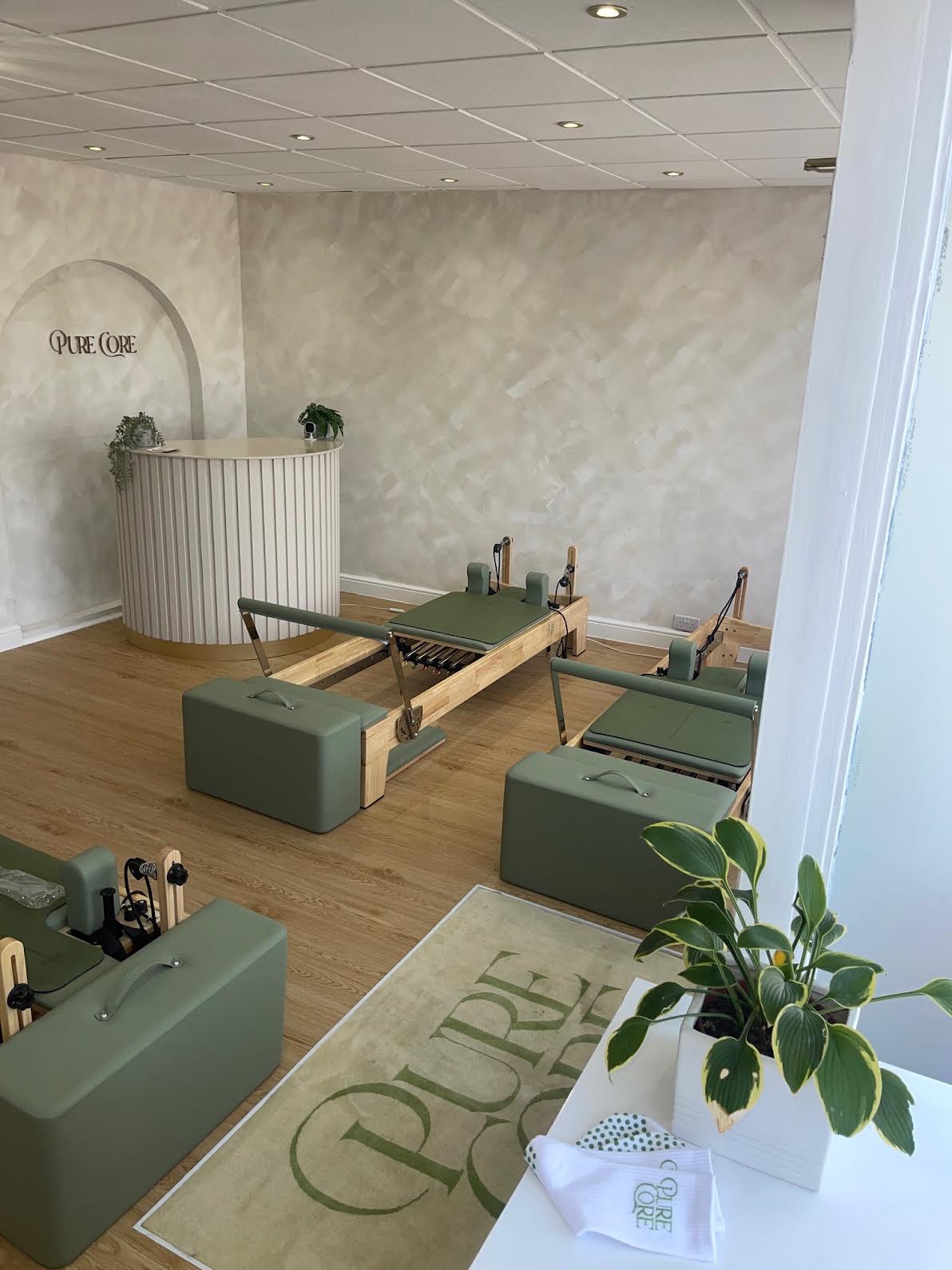 Pure Core reception desk and branded arch beside the reformer floor